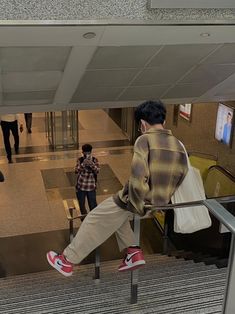 a man sitting on top of an escalator next to a woman walking down the stairs