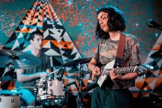 a man playing guitar in front of a drum set