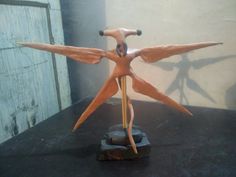 a sculpture of a bird with its wings spread out on a black countertop in front of a white wall