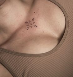 a woman's chest with a small tattoo on her left shoulder and an arrow in the middle