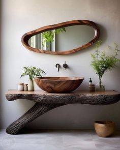 a bathroom sink sitting under a mirror next to a wooden bowl on top of a table