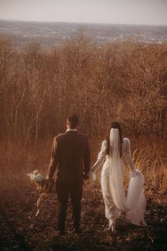 a bride and groom walk through the woods together in black - and - white photo