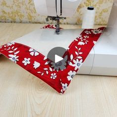 the sewing machine is making a red and white flowered piece of fabric that has been sewn on