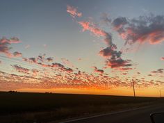 the sun is setting over an empty road