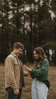 a man and woman standing together in the woods