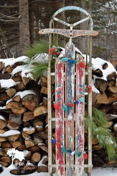 an old fashioned sled sitting in the snow next to logs and pine tree branches