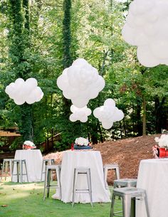 tables with white tablecloths and balloons in the shape of clouds are set up for an outdoor party