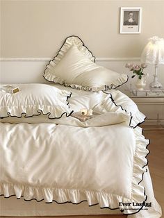 a bed with white sheets and black ruffles