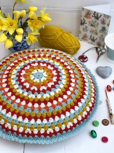 a crocheted round is sitting on the table next to some yarn and flowers