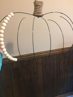 a pumpkin made out of string and wood beads on a headboard with a wooden bead decoration hanging from it's top