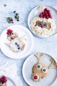 three white plates topped with pancakes covered in fruit