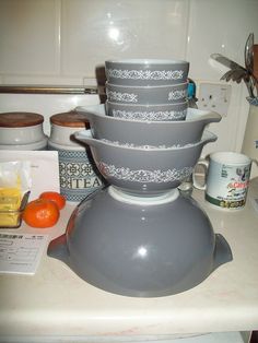 a stack of bowls sitting on top of a counter next to oranges and other kitchen items