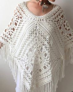 a woman wearing a white crocheted ponchy with fringes on it