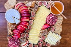 an assortment of cheeses, fruit and honey on a platter with crackers