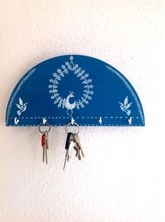 two keys are hanging from a blue wall mounted coat rack with three pairs of scissors