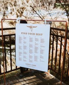 a sign that is hanging on a rail near some water and trees with the words find your seat written on it