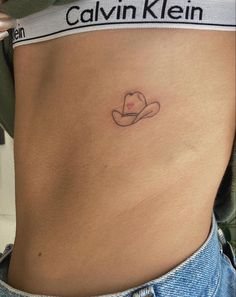 a woman's stomach with a hat tattoo on her belly and the word cavin kein written in cursive writing