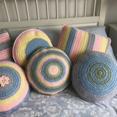 four crocheted round pillows on top of a bed with blue and pink covers