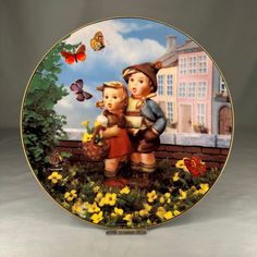 a plate with two children on it and some flowers in the grass next to them