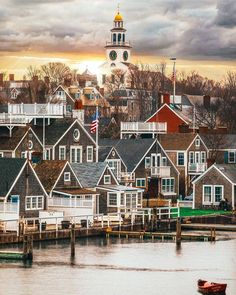 a small boat is in the water near some houses and a tower with a clock