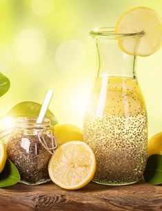 some lemons and other fruits are next to a glass pitcher with a straw in it