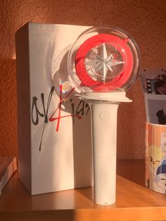 a white and red object sitting on top of a wooden table next to a box