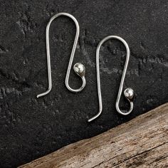 two silver hooks sitting on top of a piece of wood