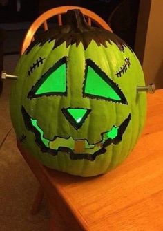 a carved pumpkin with glowing eyes on it's face sitting on a wooden table