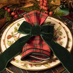 a table setting with plaid napkins and green velvet bows on the place settings for christmas dinner