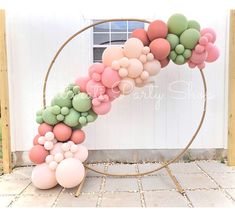 a balloon arch with pink, green and white balloons in the shape of a circle