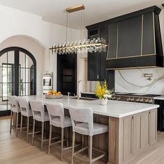 a large kitchen with black cabinets and white counter tops, along with a center island