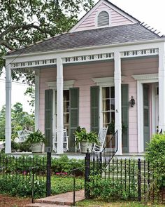 a pink house with white trim and green shutters on the front door is shown