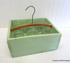 an old green box with glass jars in it and a wooden hanger on the top