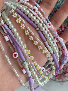 a hand is holding several bracelets with beads and charms on it's wrist