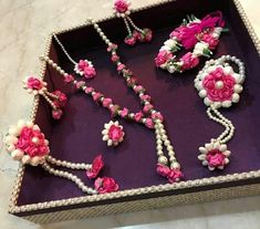 a purple tray with pink and white flowers on it, including necklaces and bracelets