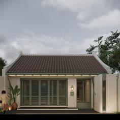 a small white house with a red tiled roof and two people standing in front of it