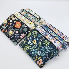 four zippered pouchs with floral designs on them, all lined up in different colors