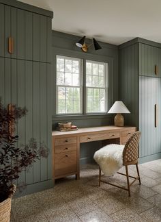 a room with green painted walls and a wooden desk in the corner, along with a white sheepskin footstool