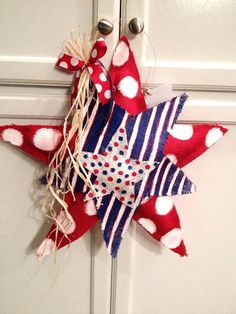 a red, white and blue star decoration hanging on the front door with two bells