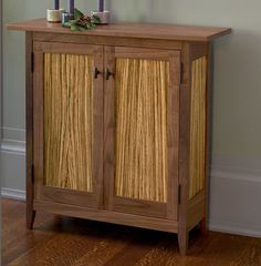 a wooden cabinet sitting on top of a hard wood floor next to a white wall