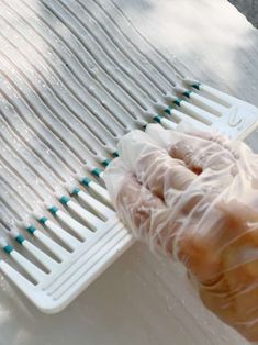 a person holding a plastic brush on top of a white tablecloth covered with water