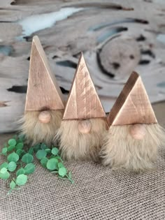 three small wooden gnomes with long hair on top of a burlied cloth