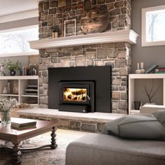 a living room filled with furniture and a fire place next to a stone wall mounted fireplace