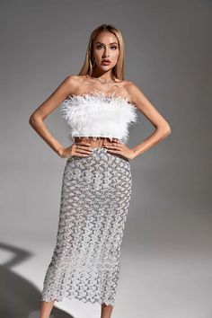 a woman in a white top and silver skirt posing for a fashion magazine photo shoot