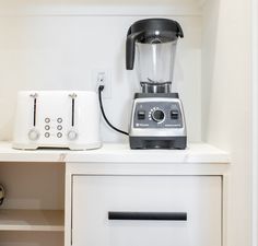 a blender sitting on top of a white counter next to a toaster oven