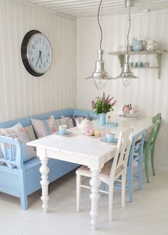 a white table with blue chairs around it and a clock on the wall behind it