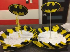 two paper plates that have batman decorations on top of each one, and some sticks sticking out of them