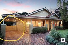 a brick driveway leading to a house at dusk