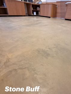 an empty room with wooden cabinets in the background and stone buff flooring on the ground