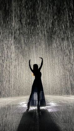 a woman standing in the rain with her arms up